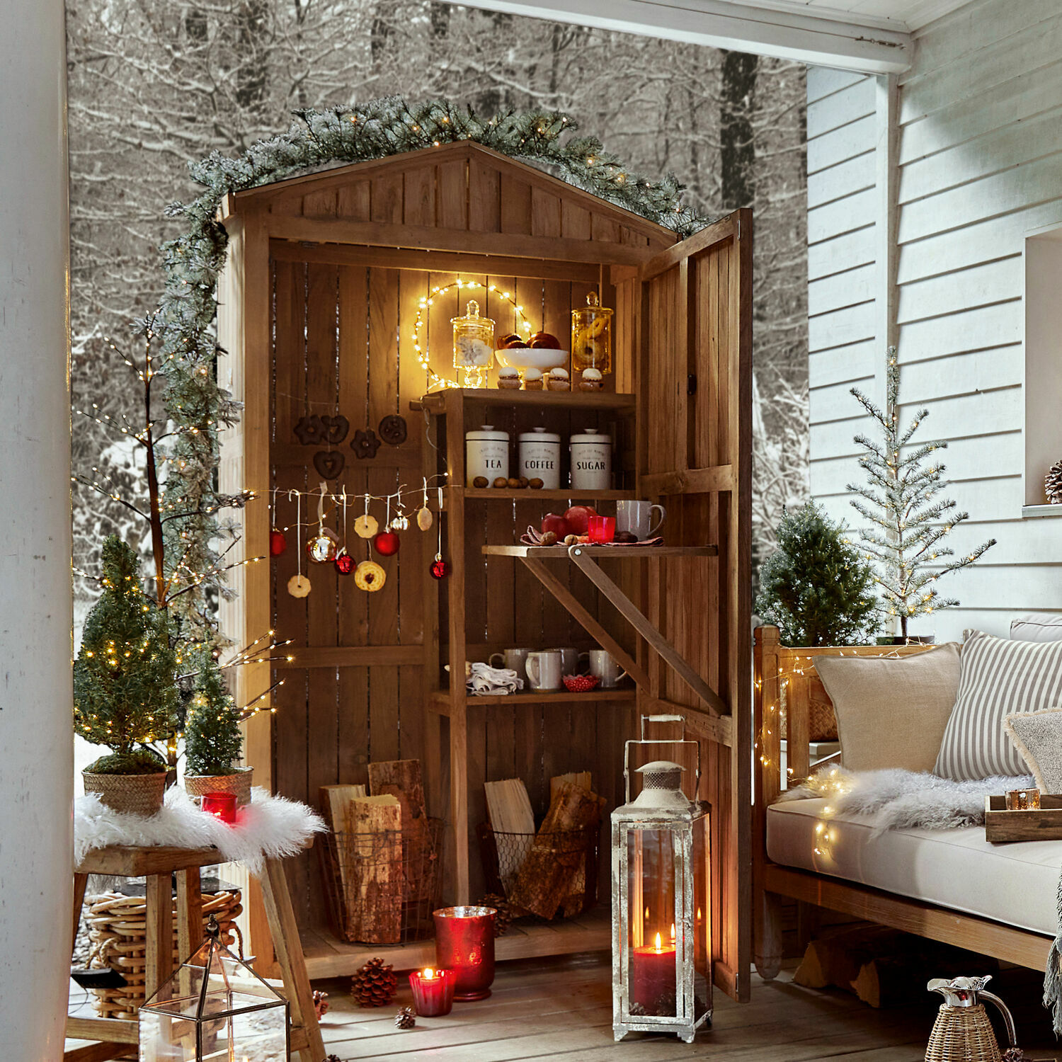 Abri en bois avec étagères décorées de guirlandes lumineuses et décorations de Noël sur une terrasse hivernale