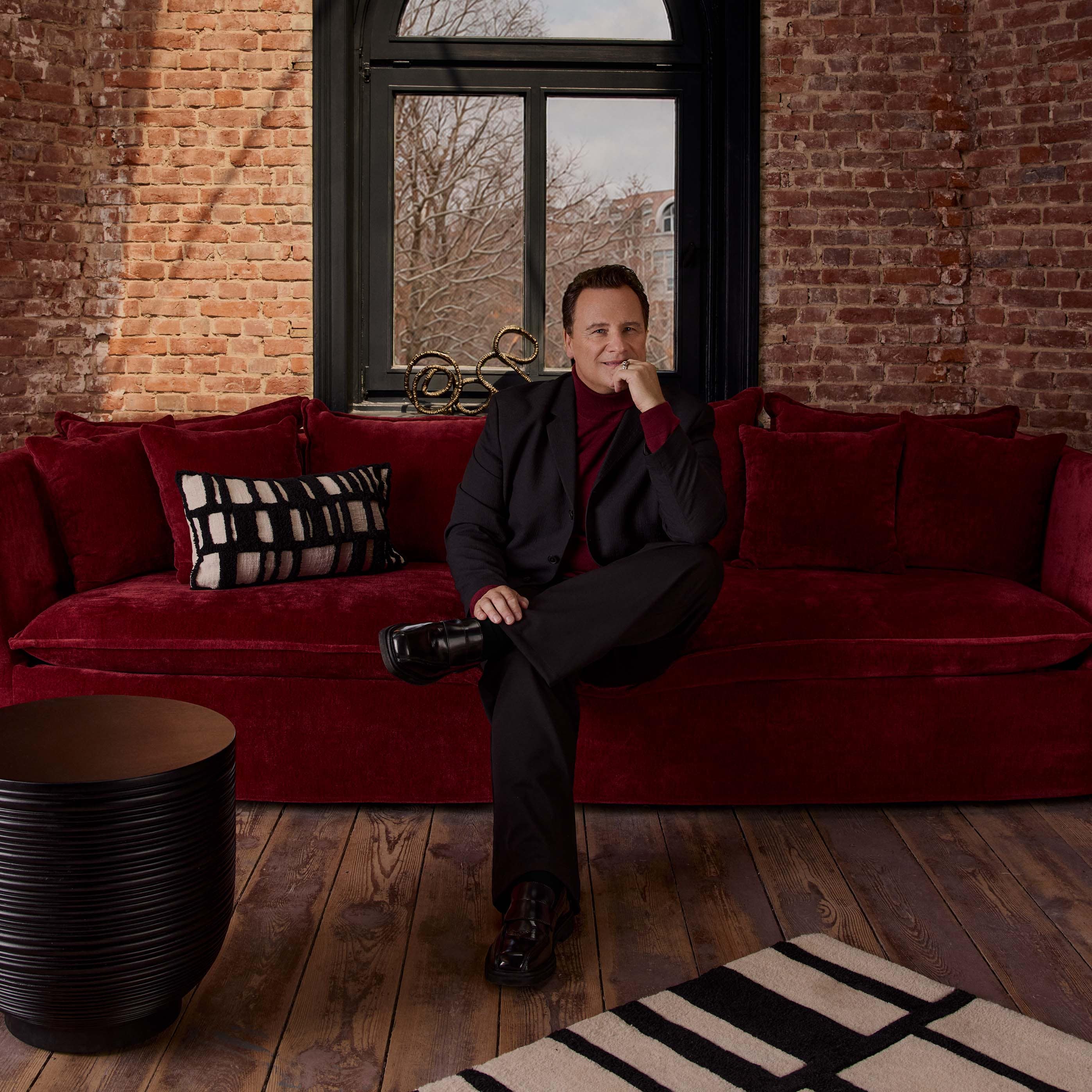 Canapé d'angle rouge en velours avec coussins et coussin décoratif noir et blanc dans un intérieur industriel
