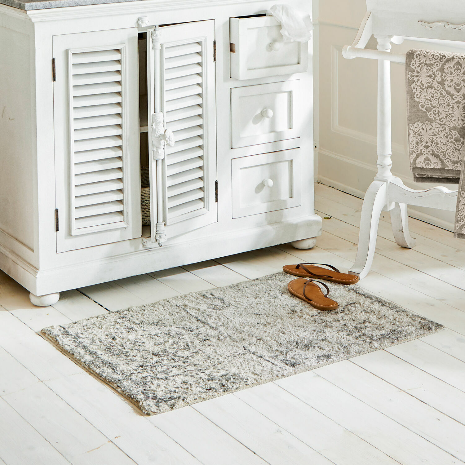 Tapis de bain Veneur Tapis gris en matériau doux sur un sol en bois blanc dans un intérieur lumineux