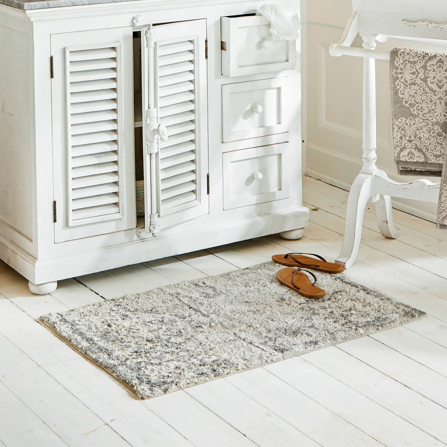 Tapis de bain Veneur Tapis gris en matériau doux sur un sol en bois blanc dans un intérieur lumineux