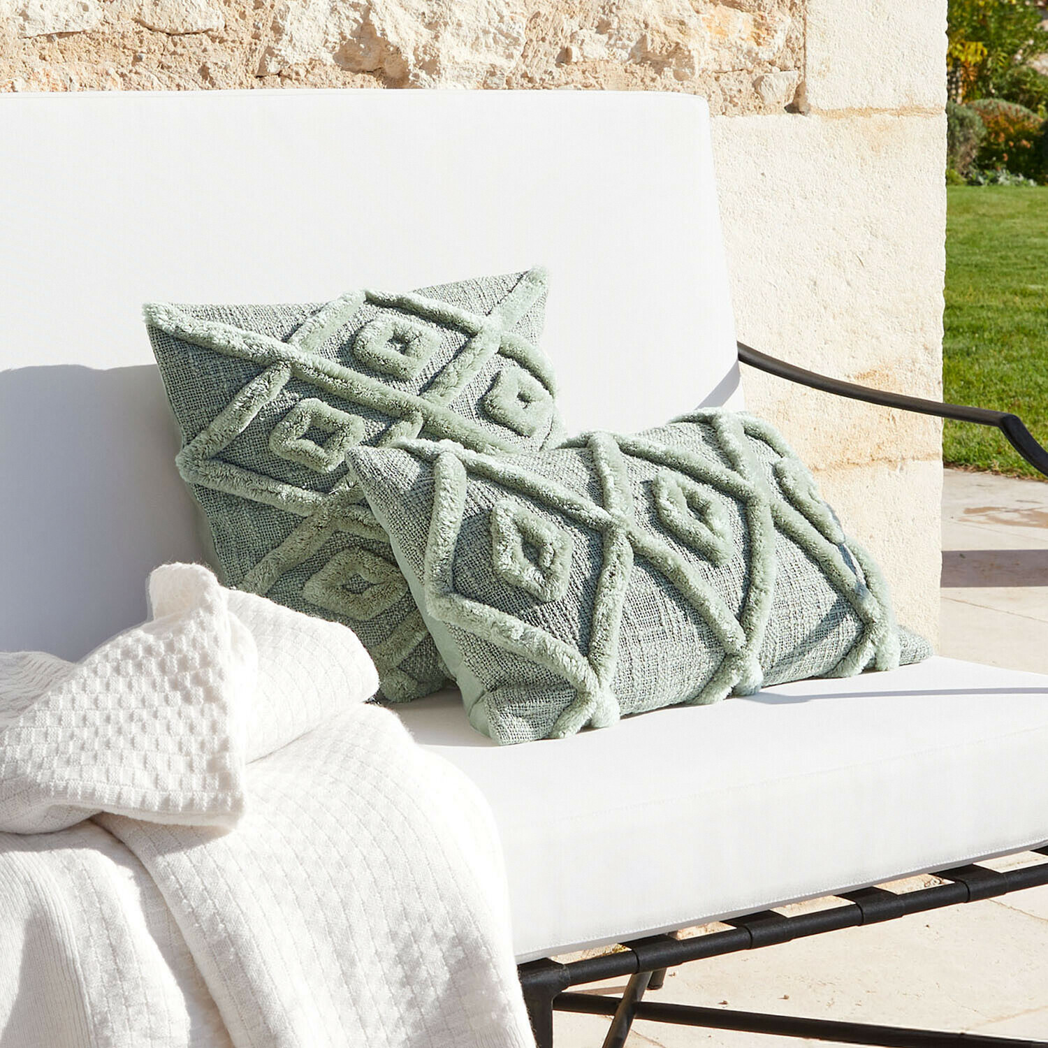 Coussins décoratifs verts menthe avec motif géométrique sur canapé blanc avec plaid, textile salon