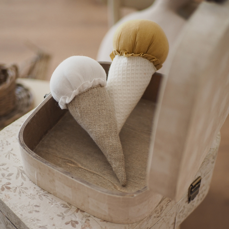Deux cônes décoratifs en tissu blanc et moutarde dans une boîte en bois sur une table