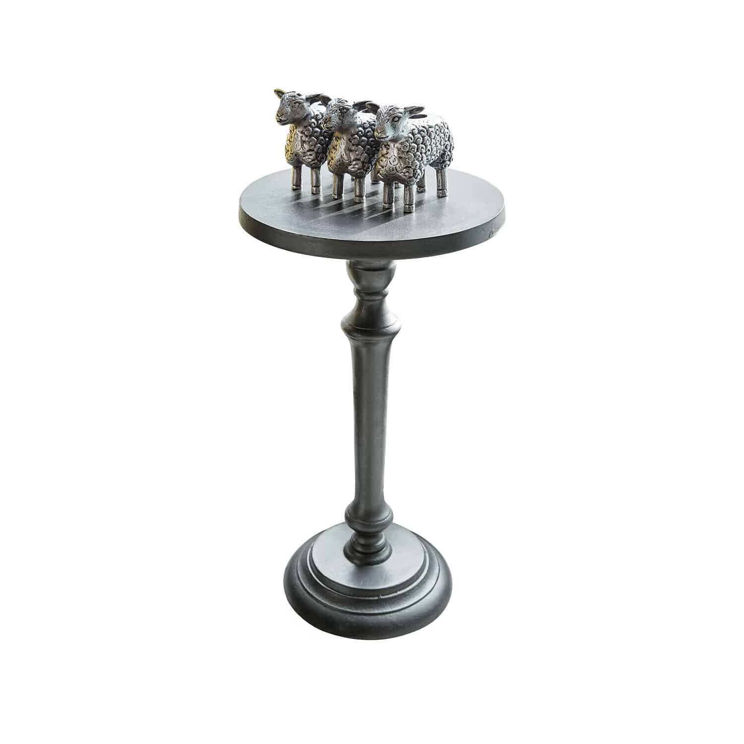 Support noir en métal avec trois figurines de moutons décoratives sur une base ronde