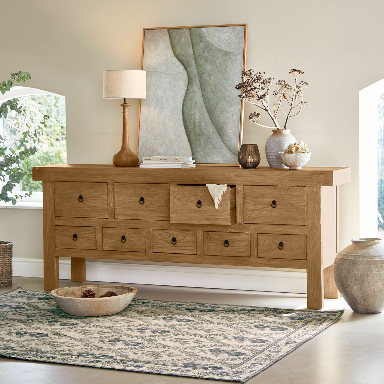 Buffet bas Eldonbury Buffet en bois naturel avec plusieurs tiroirs, décoré d'une lampe et d'un vase dans un intérieur lumineux