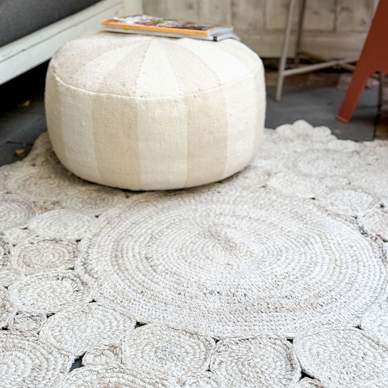 Pouf rond blanc en tissu sur tapis tissé clair, décoration intérieure cosy et naturelle