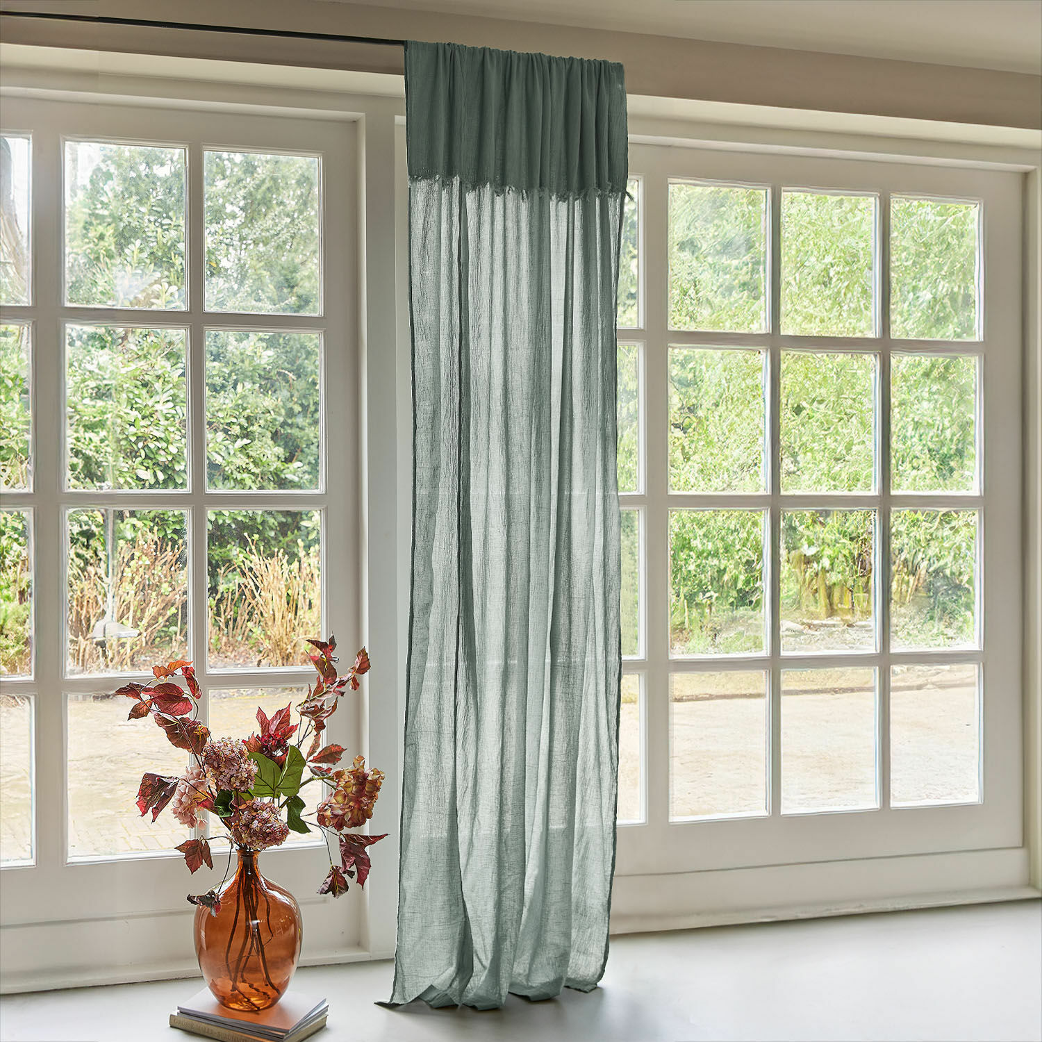 Rideau Dovinel Rideau vert transparent en lin devant une grande fenêtre avec vue sur jardin et vase à fleurs