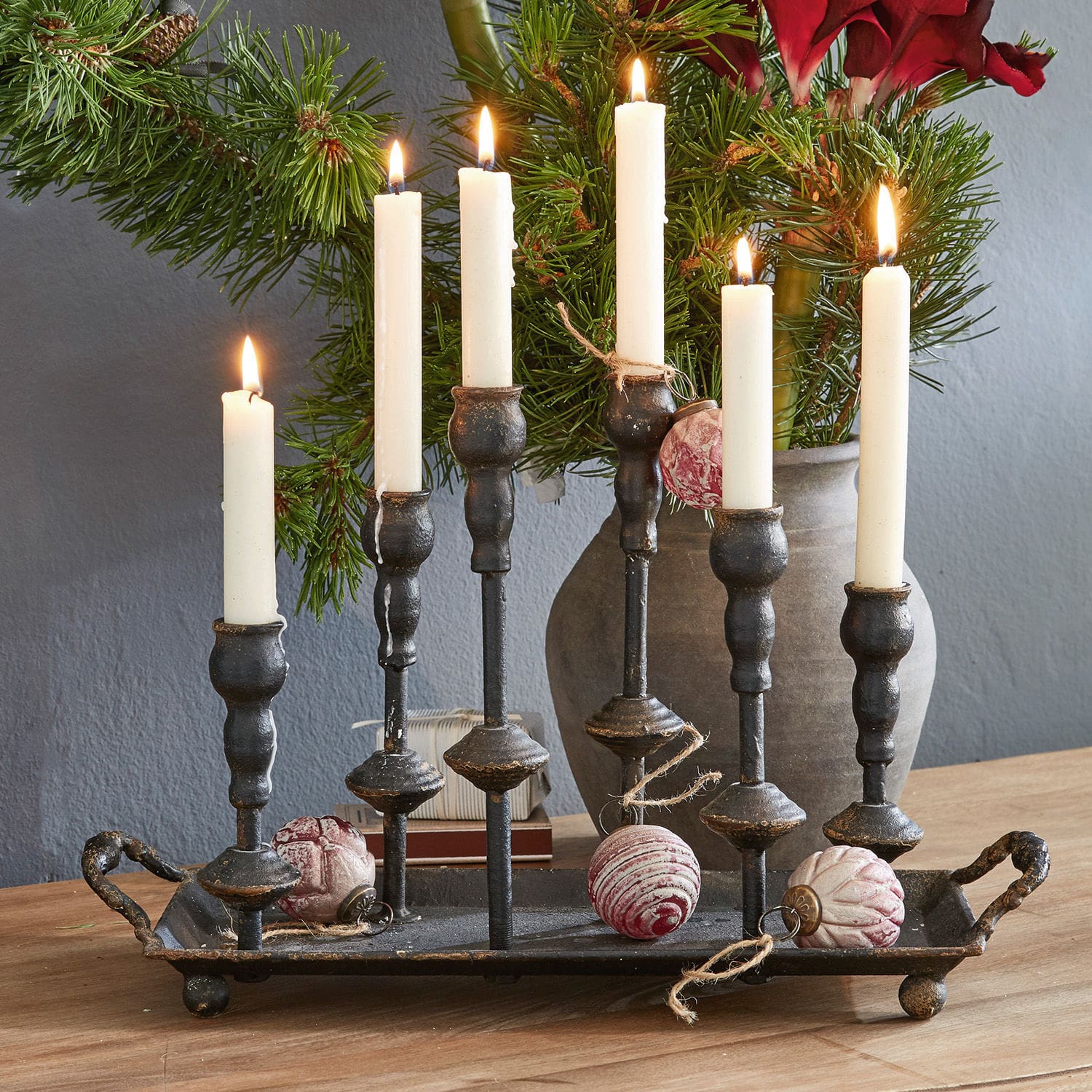 Bougeoirs Aisa Chandelier en métal noir avec six bougies blanches et décorations de Noël sur une table en bois