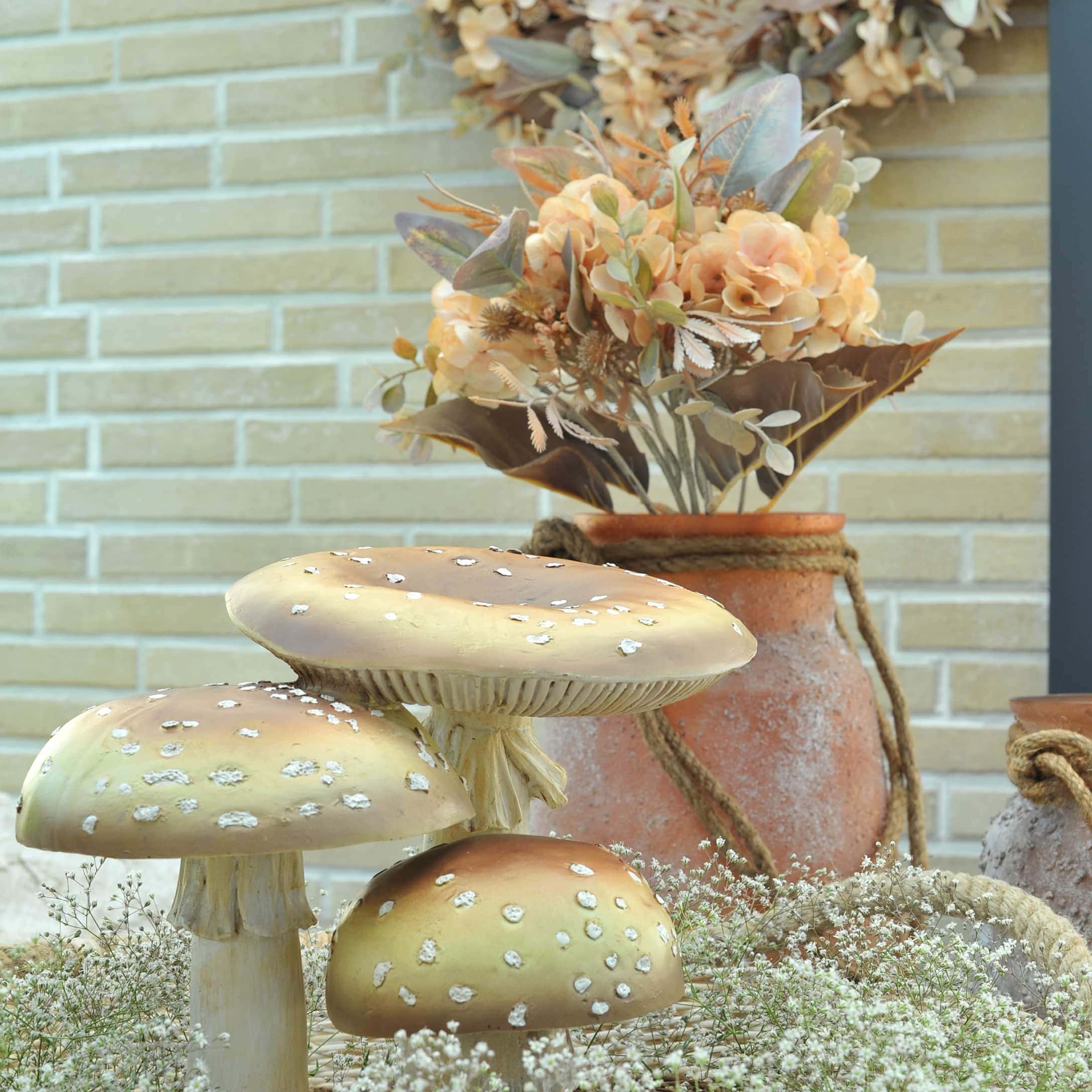 Champignons décoratifs beige avec taches blanches devant une décoration d'automne avec fleurs et vases en terre cuite