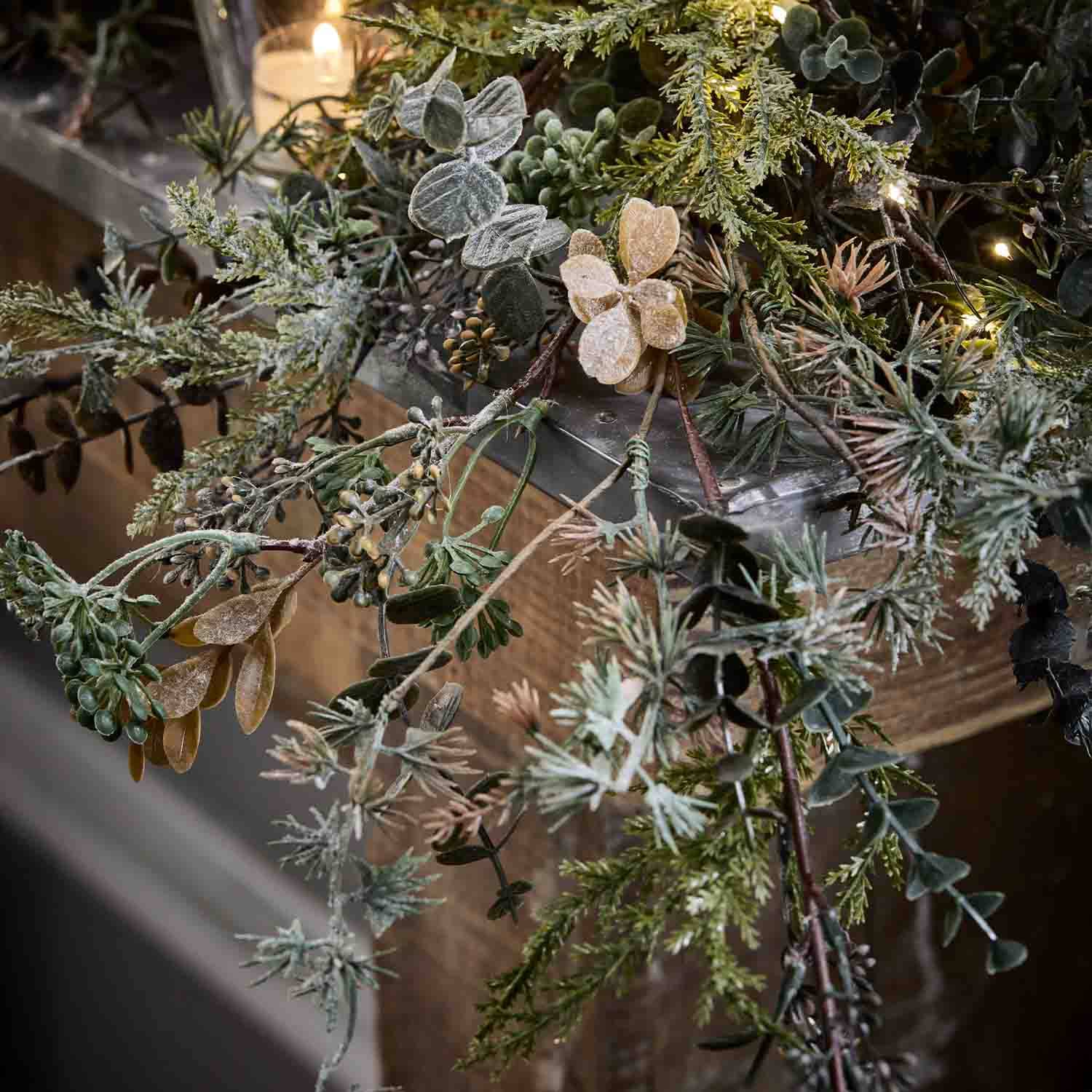 Couronne décorative en branches vertes et beige avec éclairage LED doux sur fond en bois