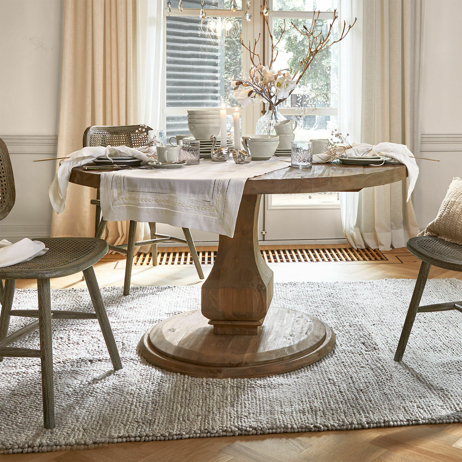 Table Alderwick Table ronde en bois avec nappe blanche et décorations dans une salle à manger lumineuse et chaleureuse
