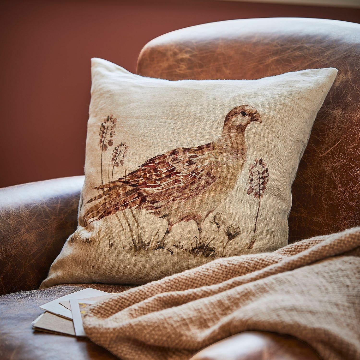 Housse de coussin Vivoso Coussin en lin beige avec impression d'oiseau brun posé sur un fauteuil en cuir marron