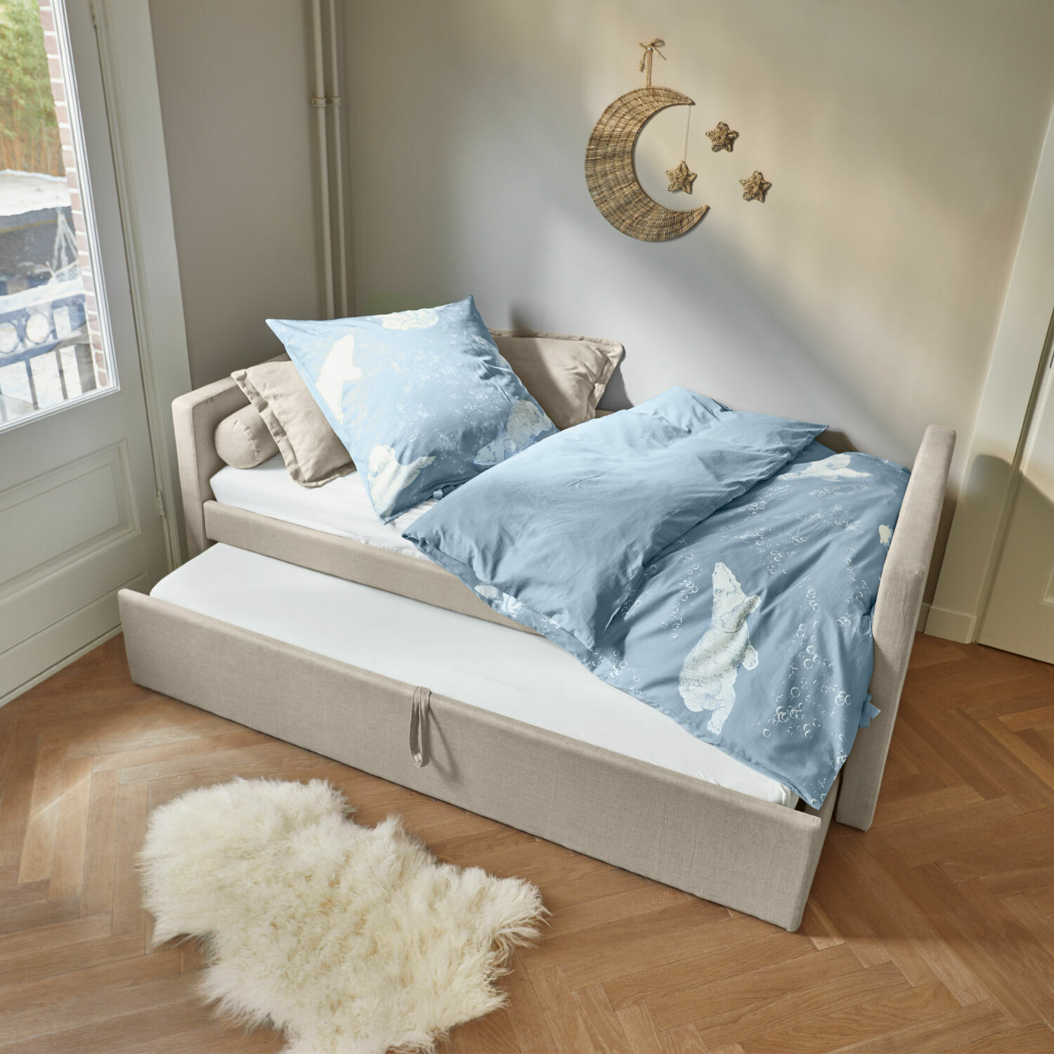 Lit Thistlewood Lit beige avec matelas gigogne et linge de lit bleu à motif ours polaire dans une chambre lumineuse.