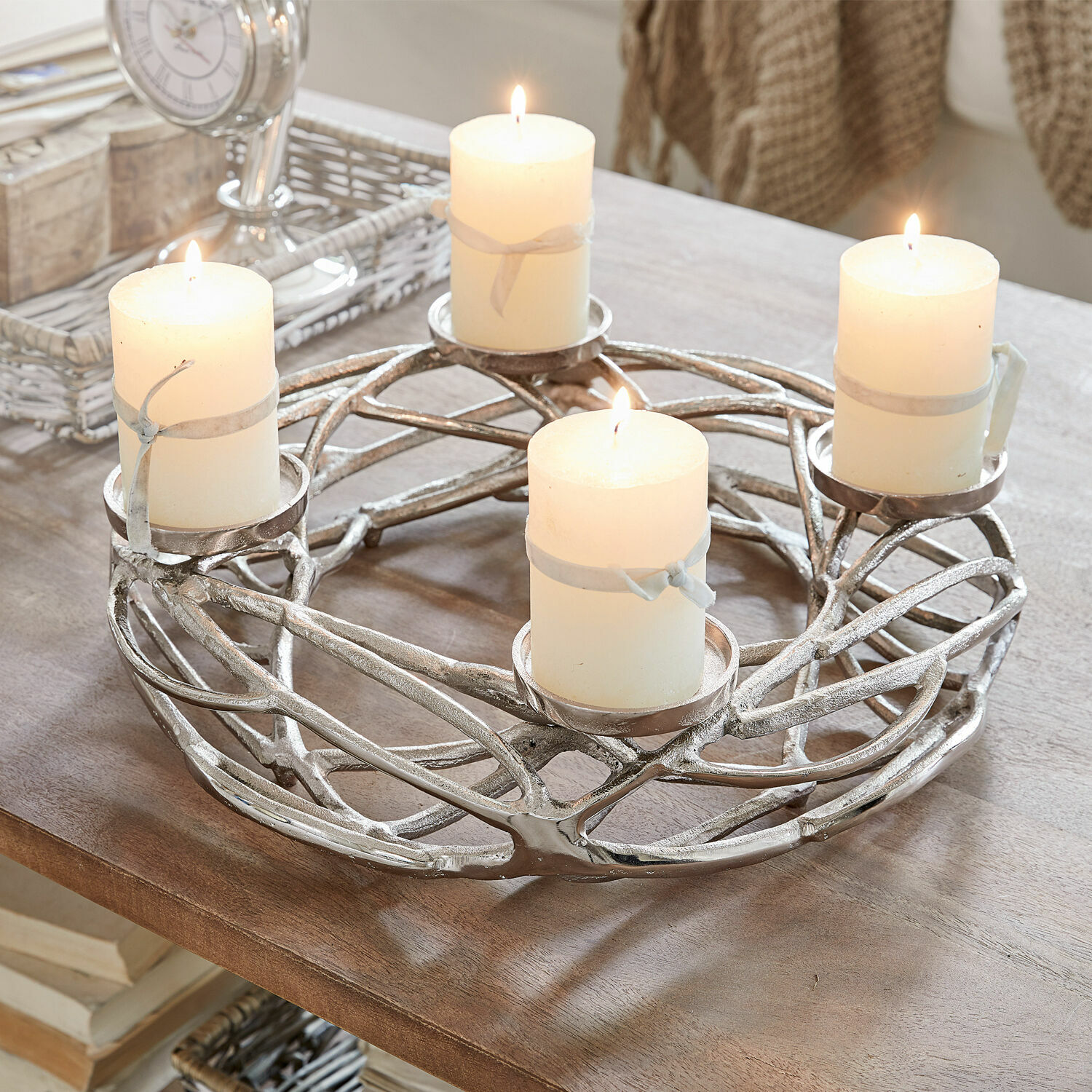 Couronne à bougies Coldfield Bougeoir en métal argenté avec quatre bougies blanches allumées sur une table en bois, décoration intérieure