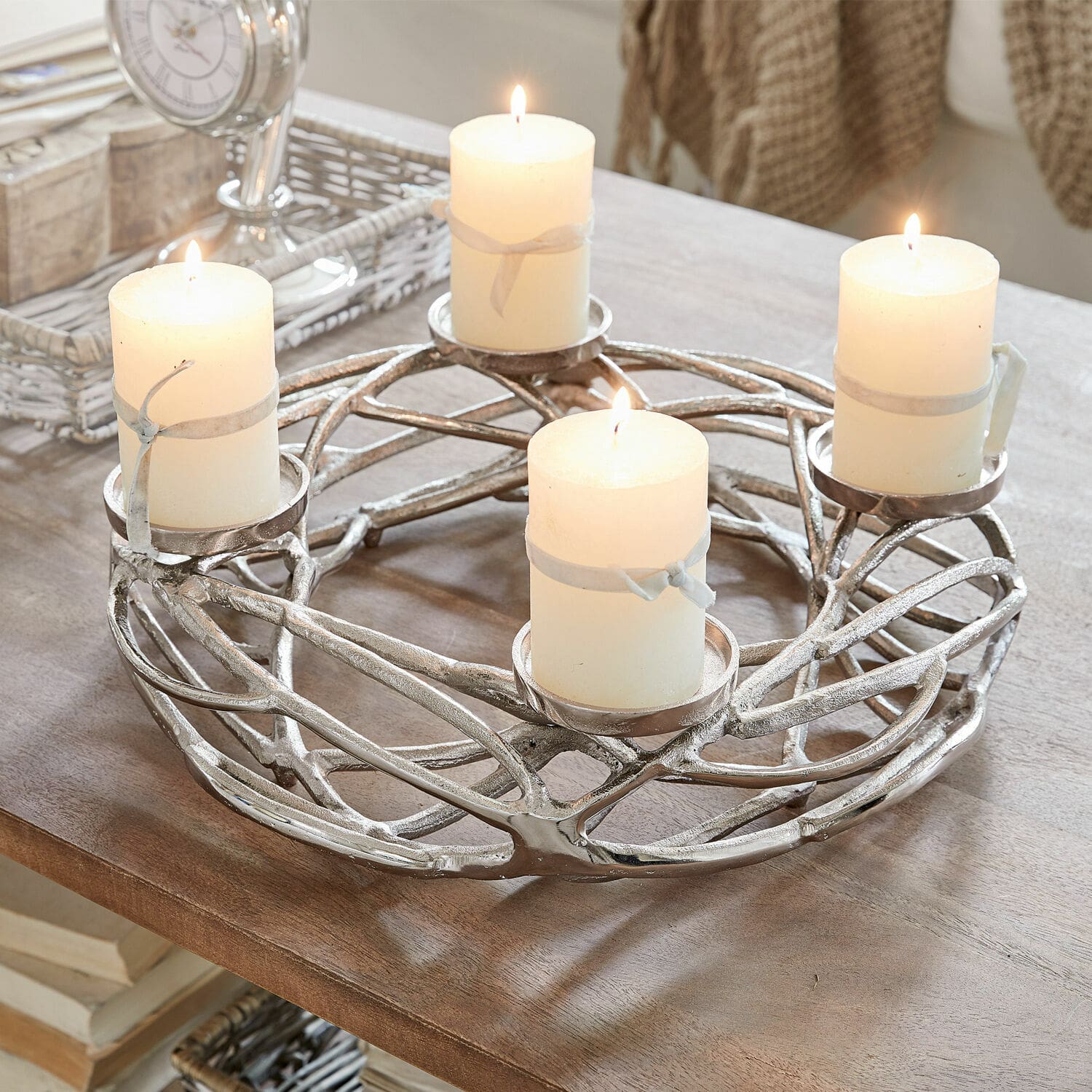 Couronne à bougies Coldfield Bougeoir en métal argenté avec quatre bougies blanches allumées sur une table en bois, décoration intérieure