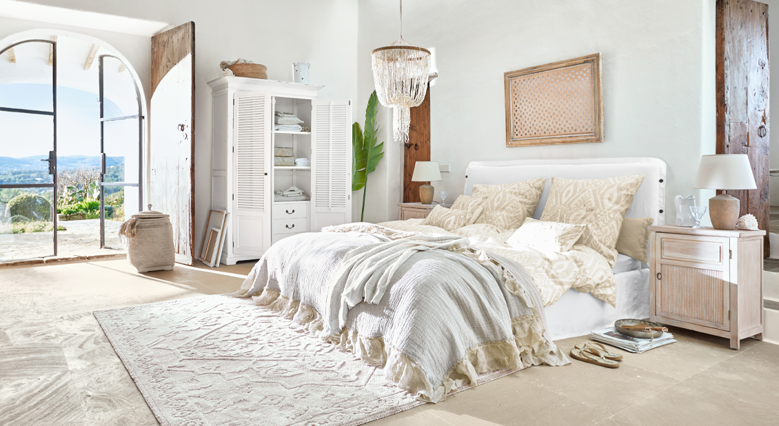 Chambre lumineuse avec lit blanc, literie beige et meubles en bois de style rustique