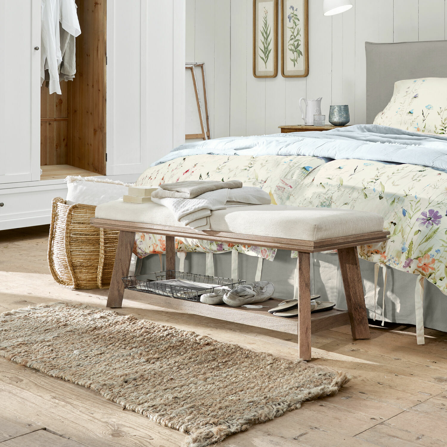 Banc Abington Banc en bois avec assise rembourrée claire dans une chambre, tapis naturel et décor floral