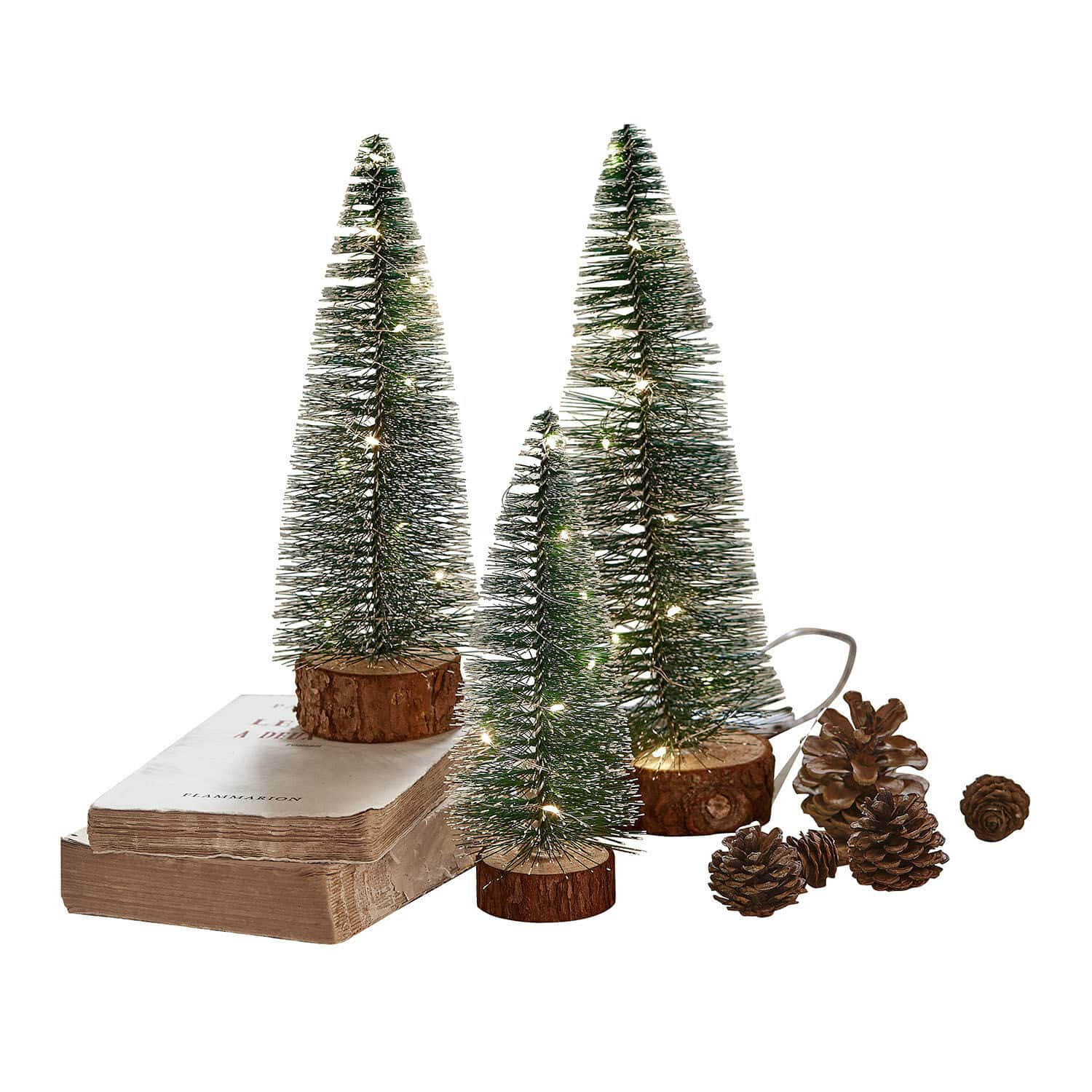 Lot de 3 sapins décoratifs à LED Thalindra Petits sapins décoratifs verts avec lumières LED sur socles en bois, accompagnés de pommes de pin et livres