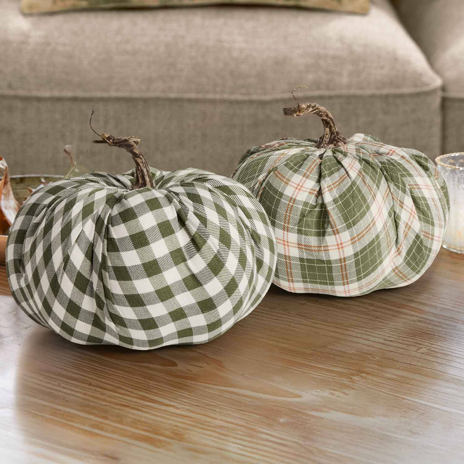 Deux citrouilles décoratives en tissu à carreaux vert et blanc avec tiges naturelles sur une table en bois