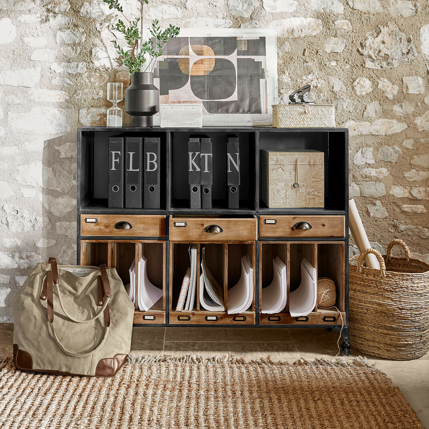 Meuble en métal noir et bois avec tiroirs et classeurs devant un mur en pierre pour rangement vintage