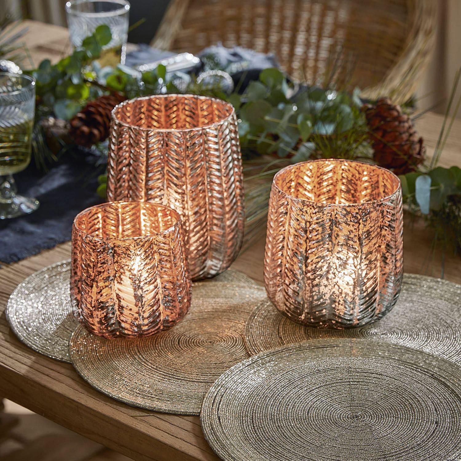 Lot de 3 photophores Centrès Ensemble de trois photophores en verre cuivré avec motif feuille sur table en bois décorée pour les fêtes