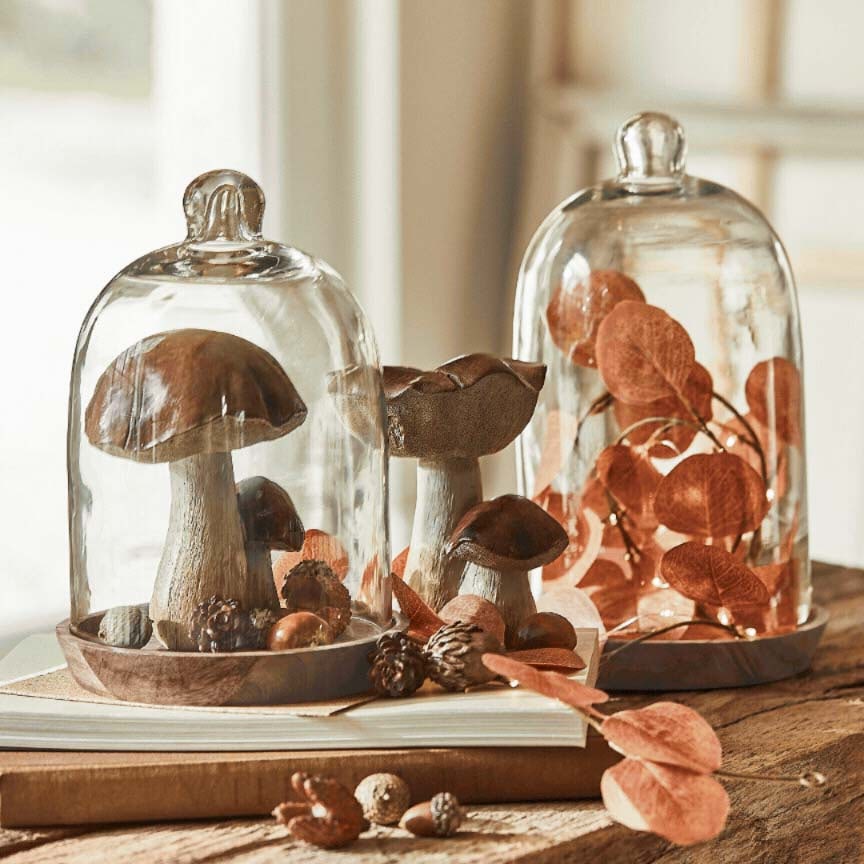 Champignons décoratifs et feuilles sous cloches en verre sur socle en bois, décoration automnale de table