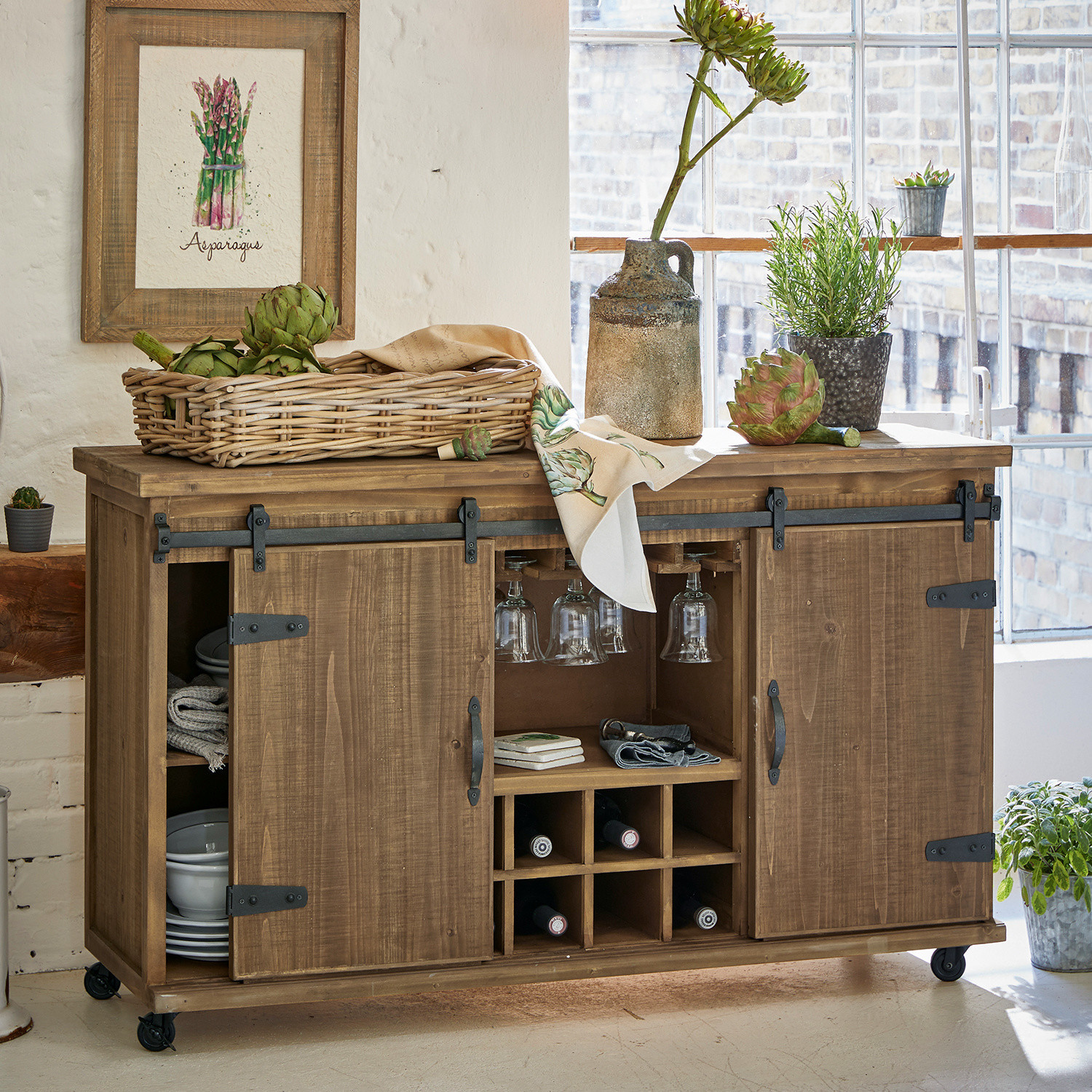 Commode Grasse Buffet en bois sur roulettes avec rangement à vin et verres, décoré de plantes vertes et panier de légumes