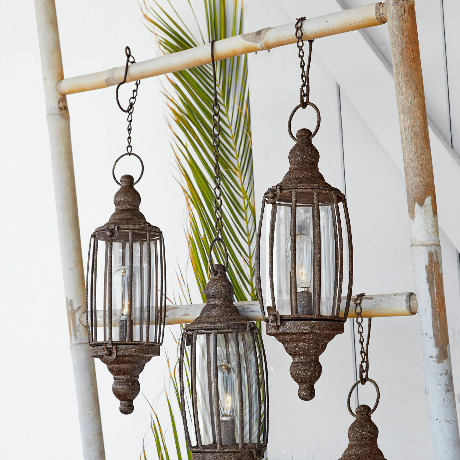 Lot de 2 lanternes LED à suspendre Flavin Ensemble de quatre lanternes suspendues en métal rouillé sur une échelle en bambou, décoration intérieure
