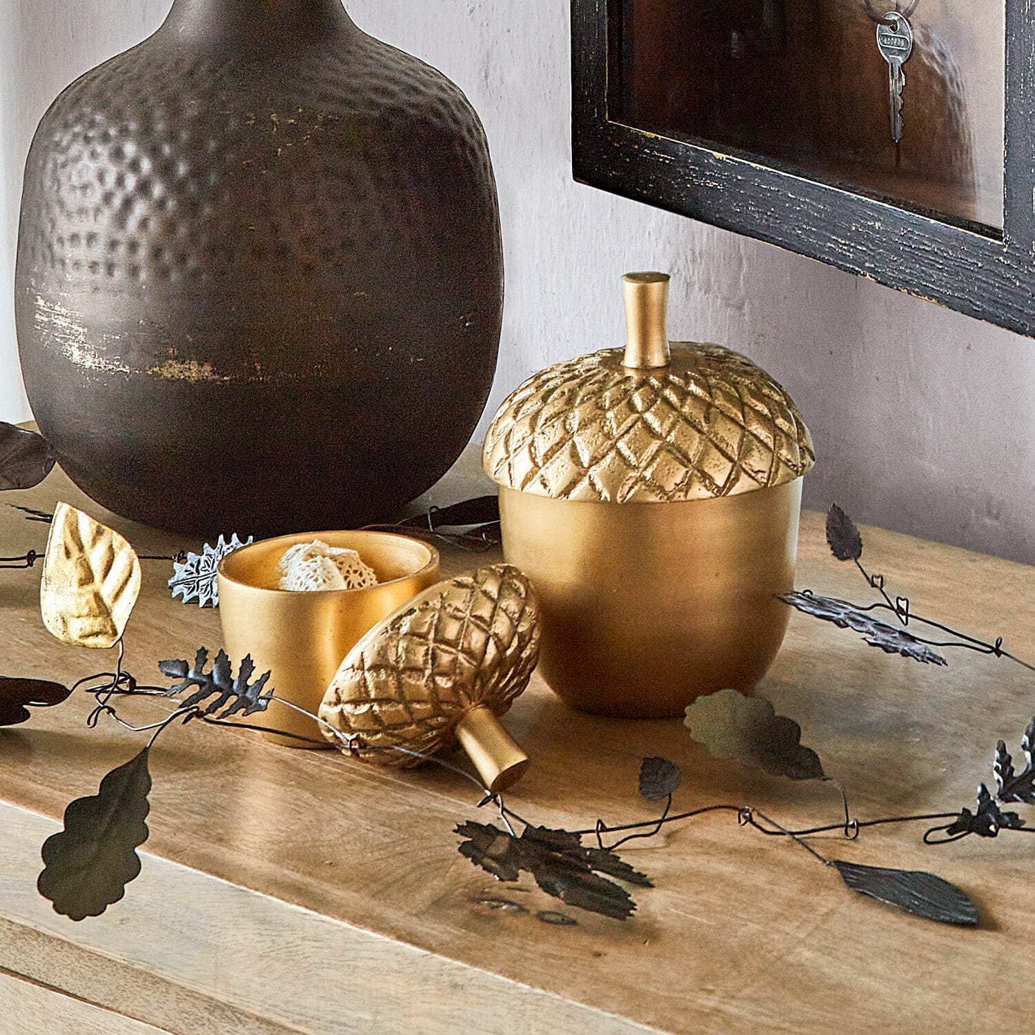 Lot de 2 boîtes Selmar Boîte en métal doré en forme de gland sur une surface en bois avec décoration de feuilles