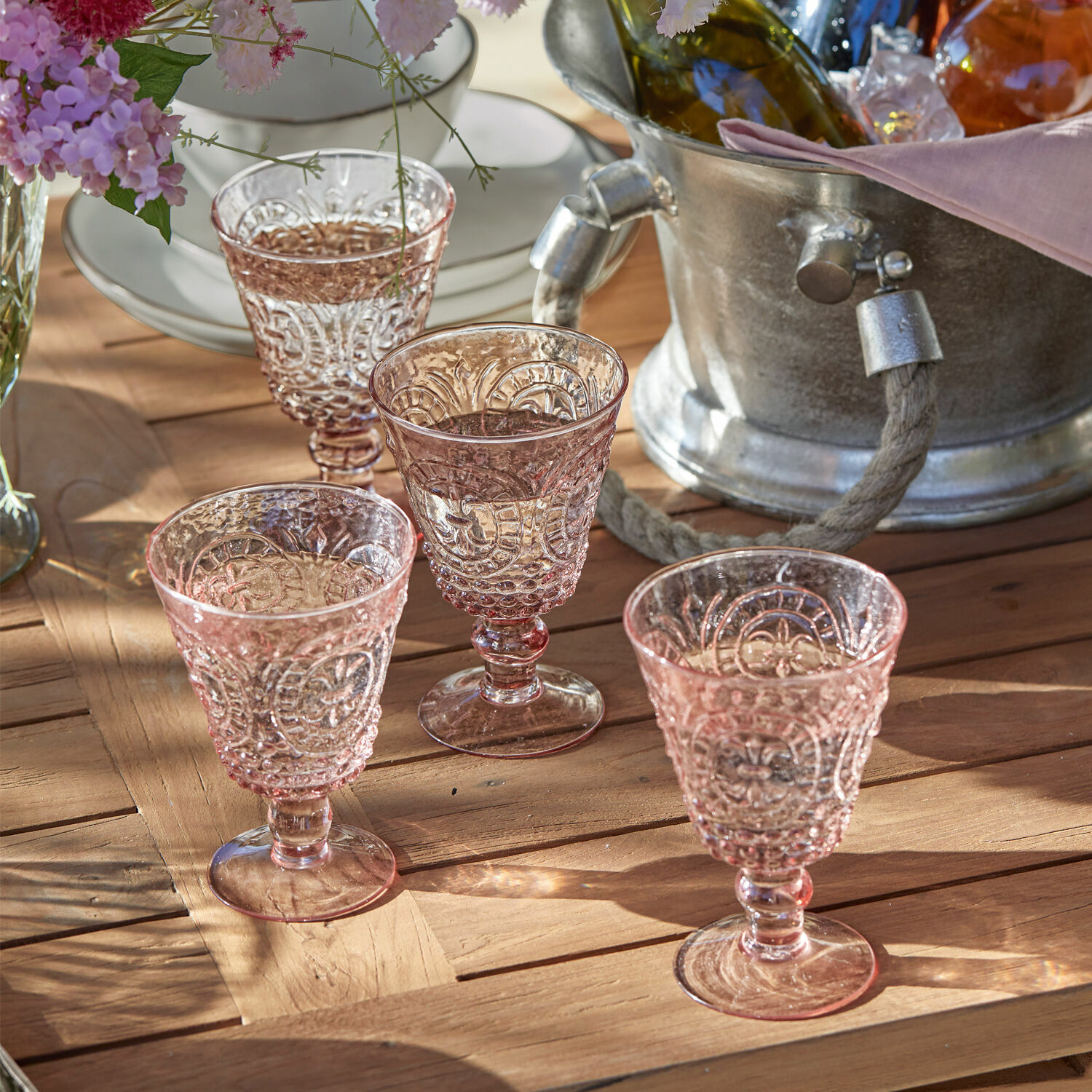 Lot de 4 verres à vin Sarton Ensemble de quatre verres roses en verre embossé sur une table en bois, décoration de table élégante
