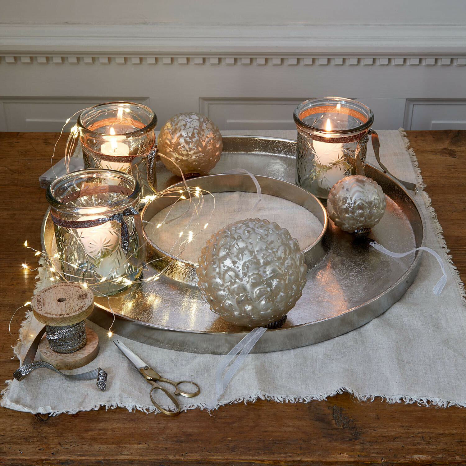 Plateau à bougies Velarosas Plateau en métal argenté avec bougies décoratives et boules en verre sur table en bois avec guirlande LED