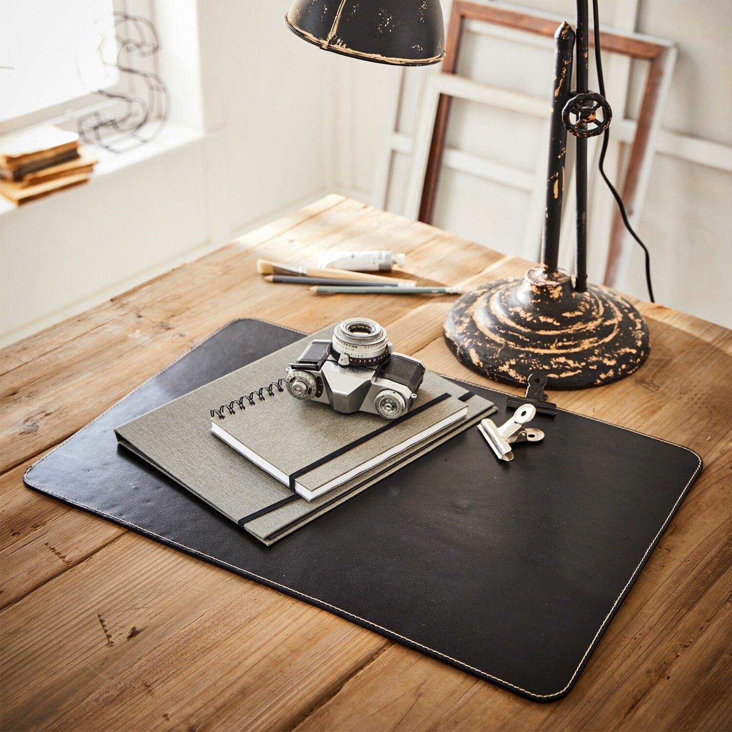 Sous-main Jansen Sous-main en cuir noir avec carnets et appareil photo vintage sur une table en bois clair