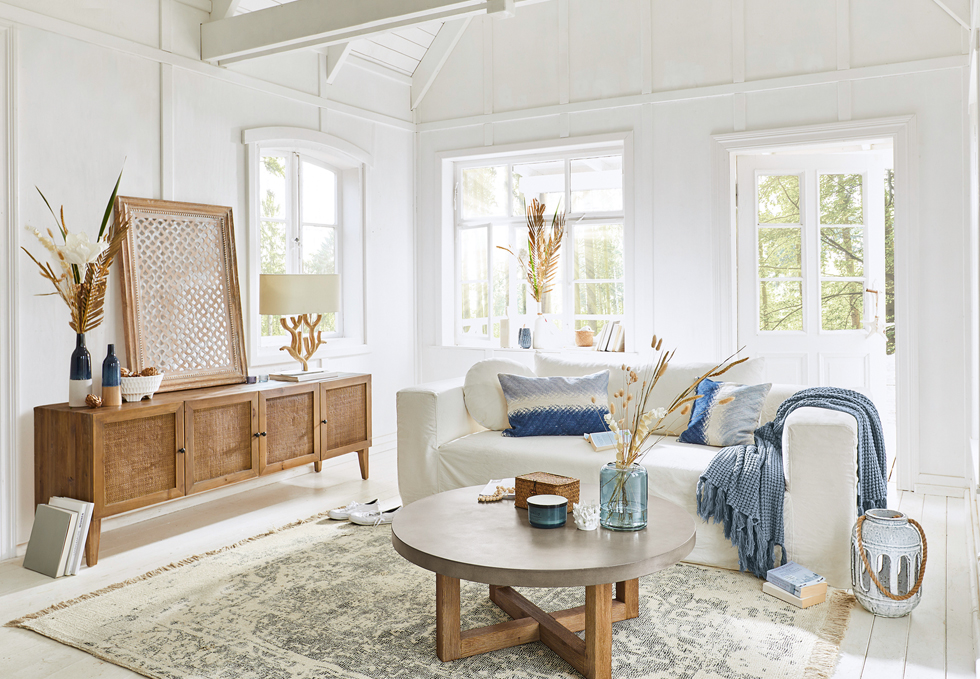 Salon lumineux style marin avec canapé blanc, buffet en bois et accessoires bleus