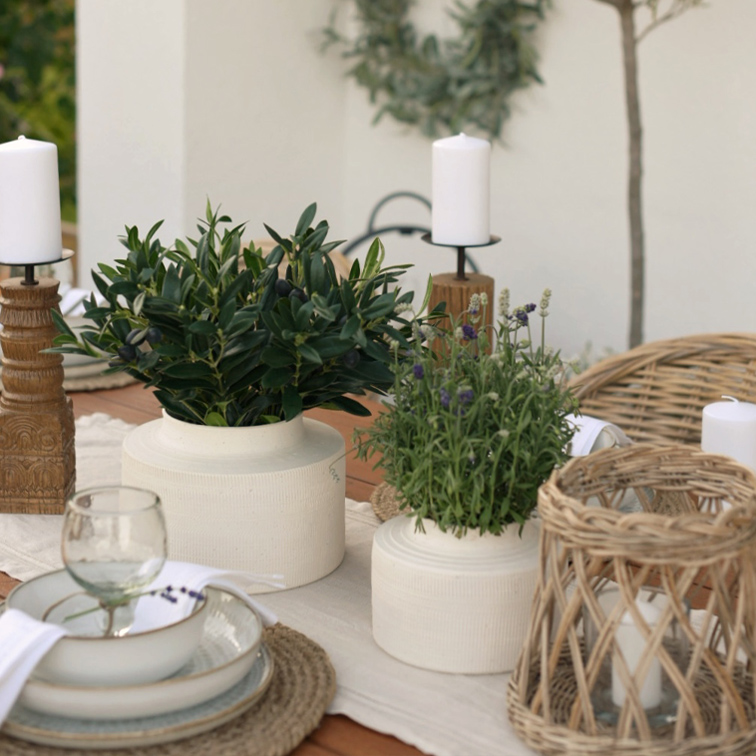Pots en céramique blanche avec plantes vertes sur table en bois décorée de bougeoirs naturels