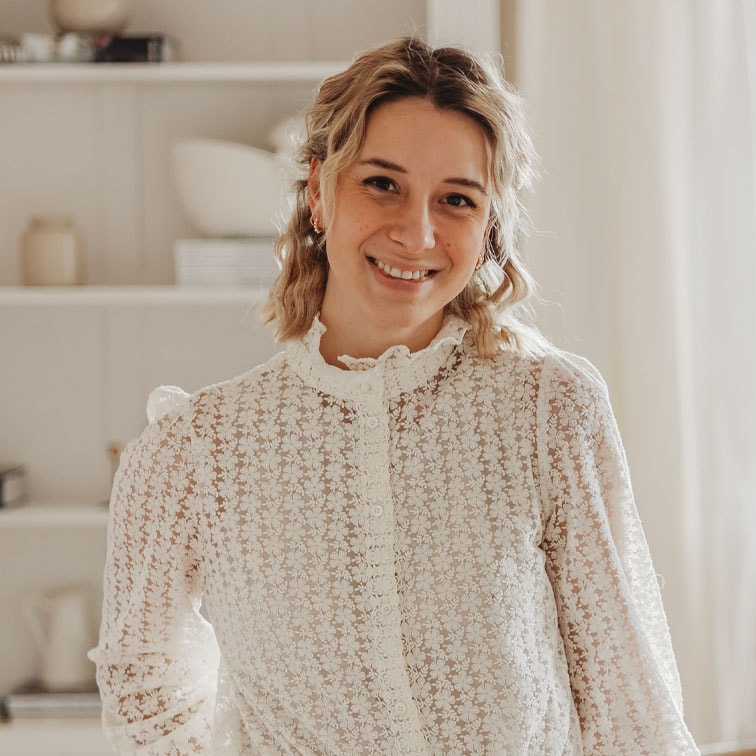 Femme portant un chemisier en dentelle blanche à motif floral dans un intérieur lumineux