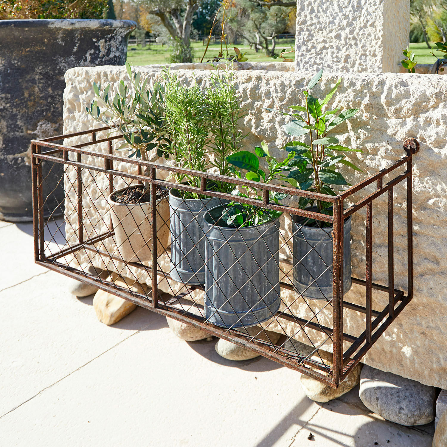 Jardinière Edington Jardinière en métal rouillé avec pots et plantes vertes sur terrasse ensoleillée