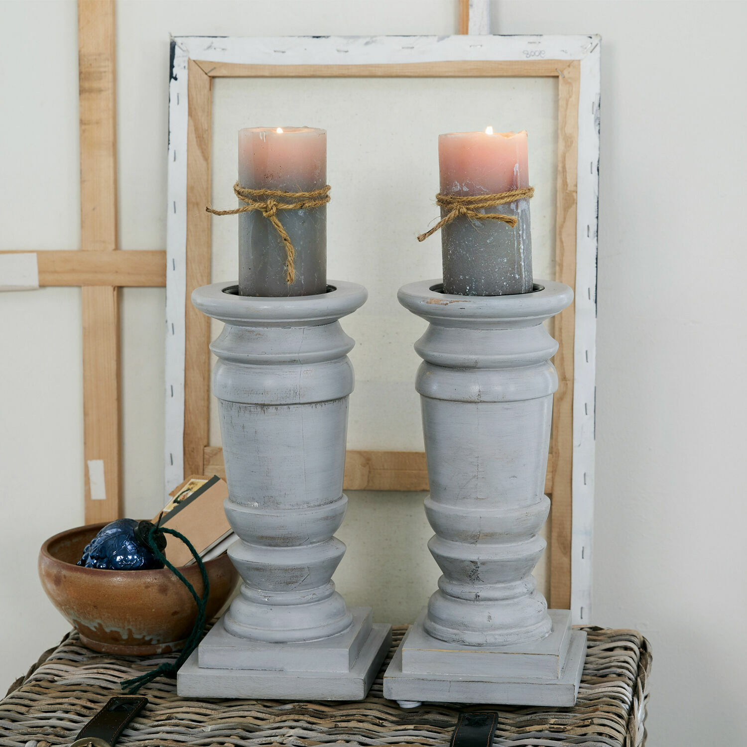 Lot de 2 bougeoirs Lobata Paire de bougeoirs en bois gris avec bougies grises et décorations en corde sur table en osier
