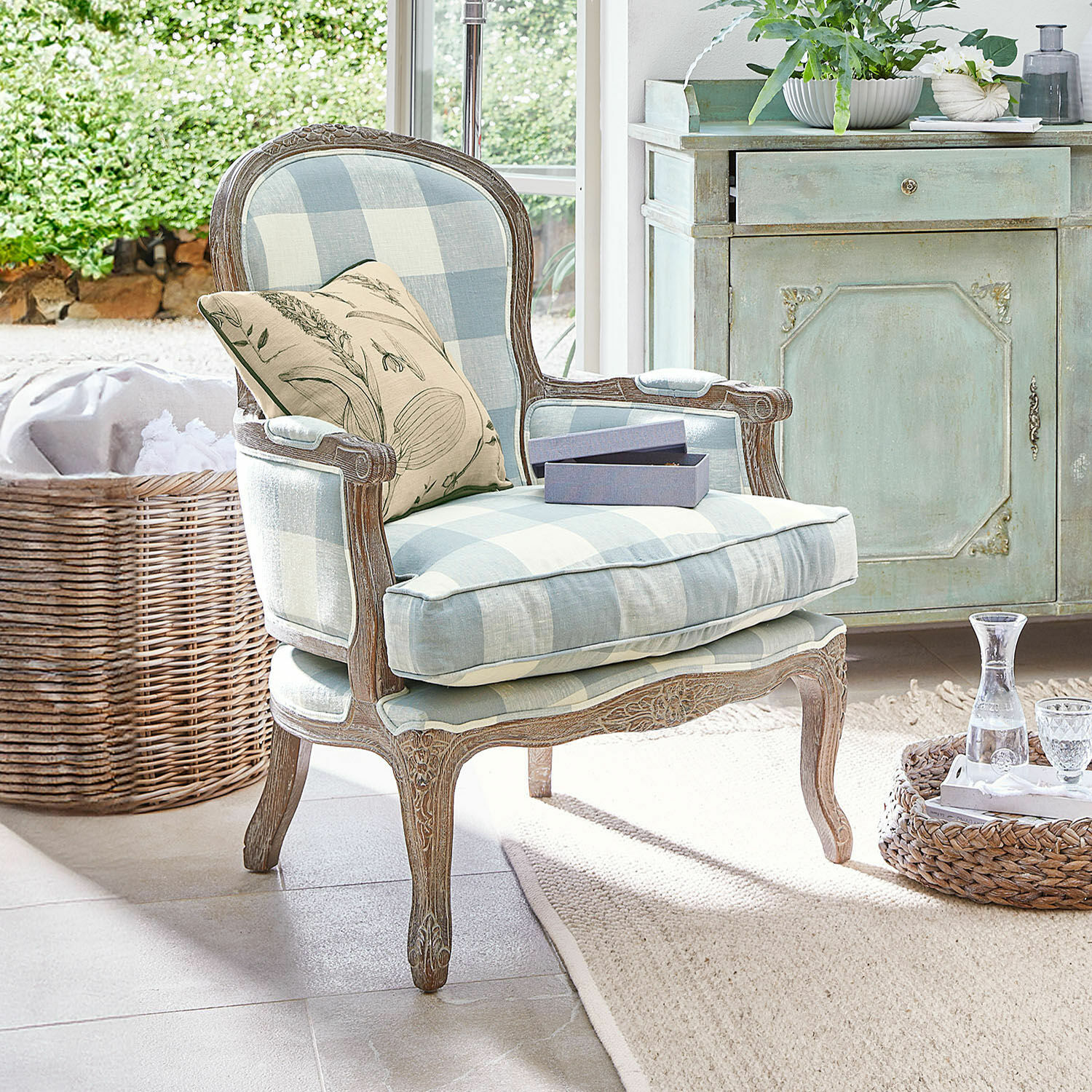 Fauteuil Quintelais Fauteuil en bois avec tissu à carreaux bleu clair et beige, coussin décoratif à motif végétal dans un intérieur lumineux
