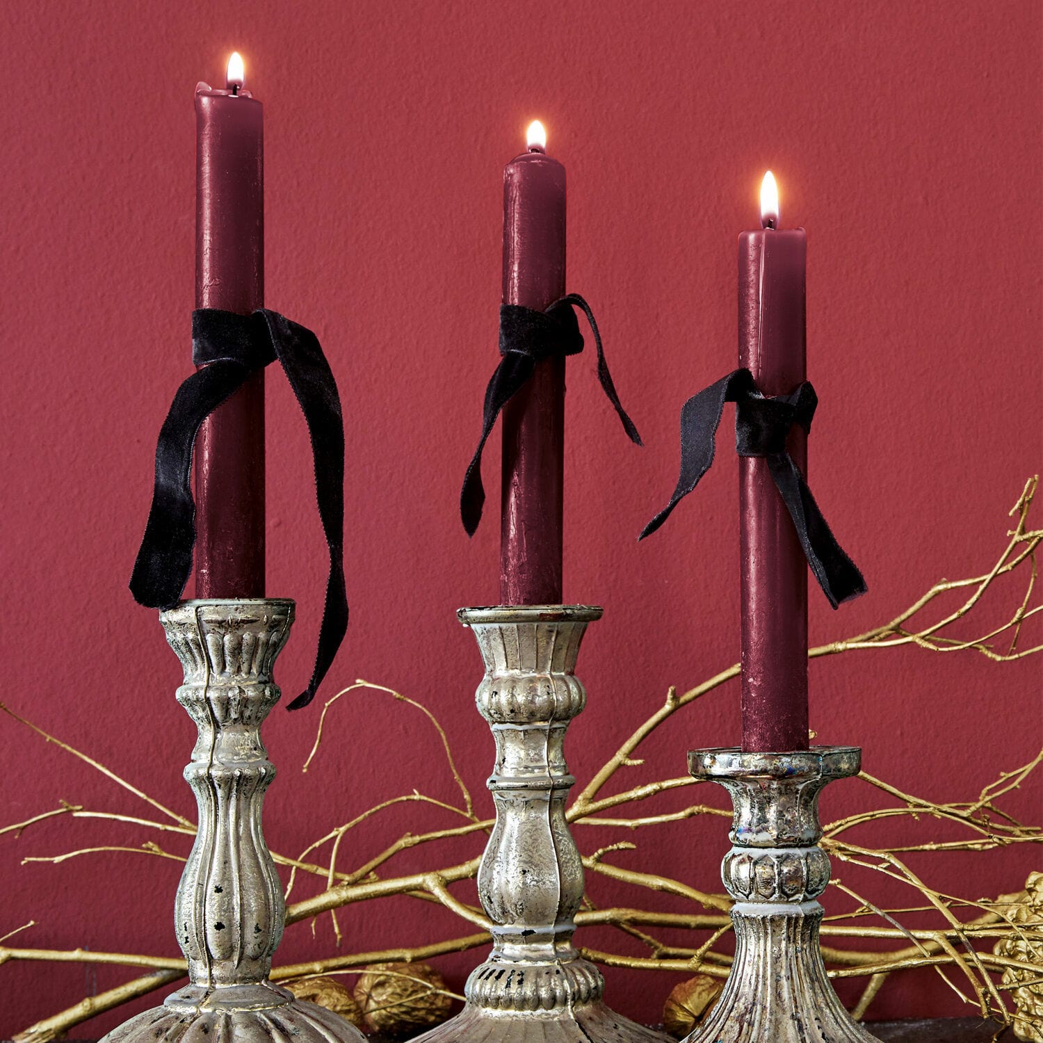 Lot de 12 bougies Bauceau Trois bougeoirs en métal argenté avec bougies bordeaux et rubans noirs sur fond rouge