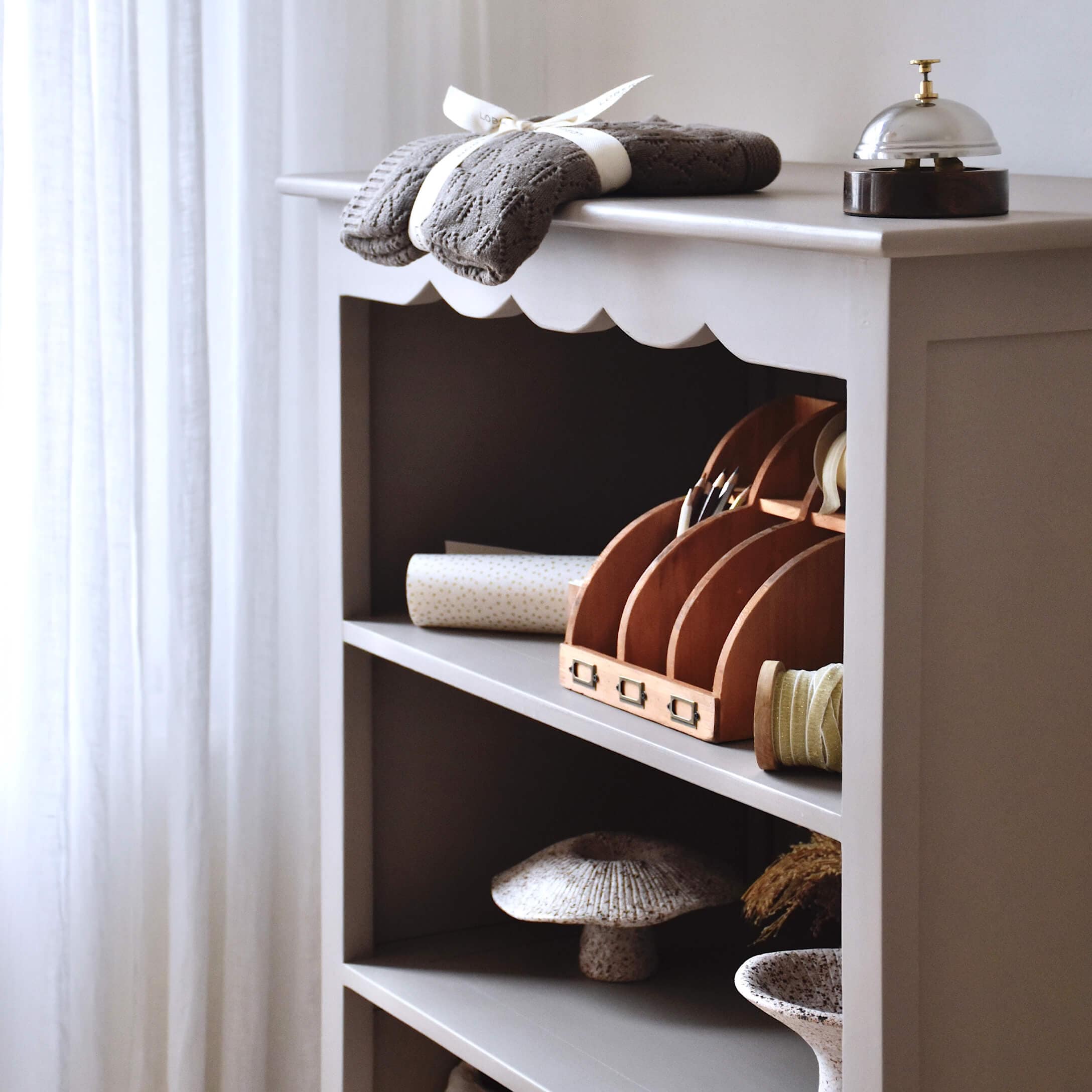 Étagère grise en bois avec objets décoratifs et tissu tricoté gris posé dessus
