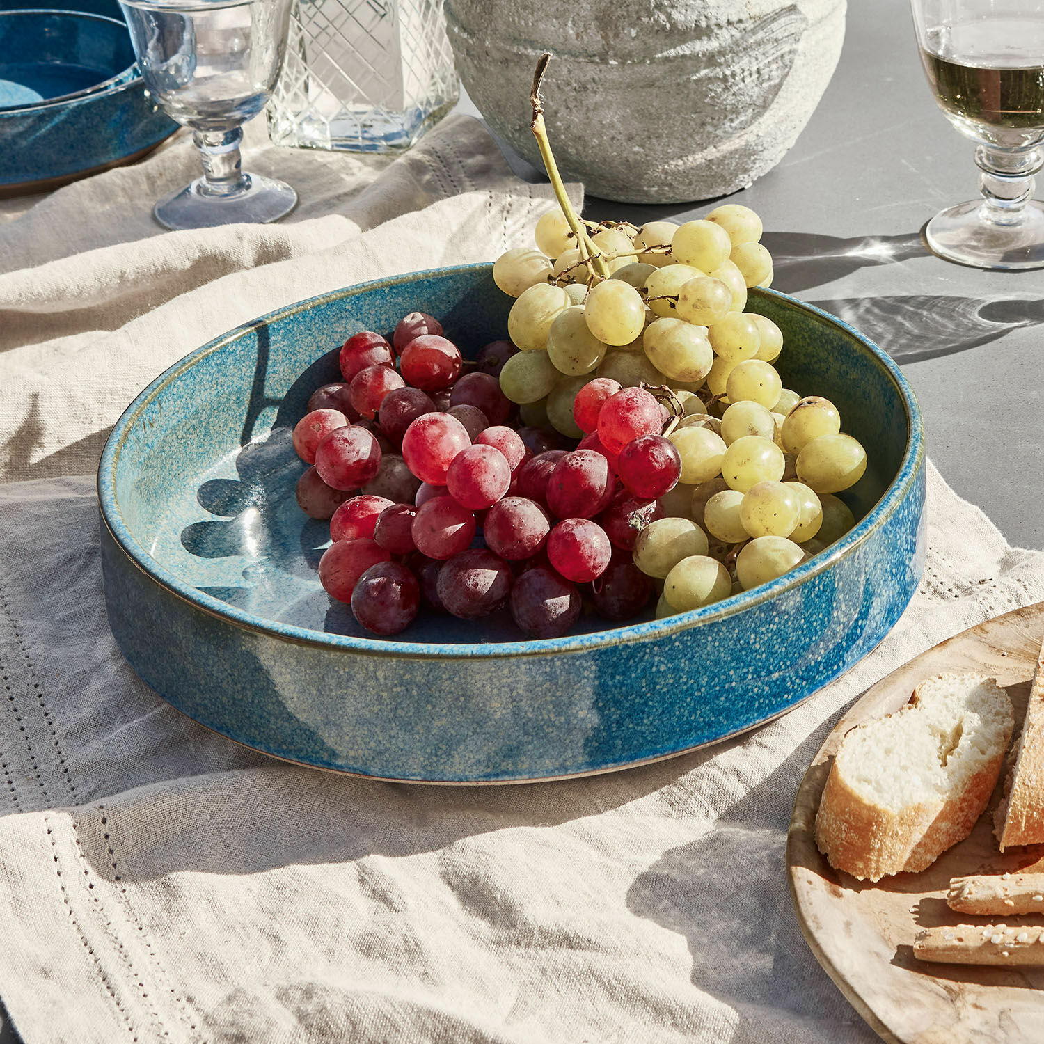Saladier Darney Grand plat en céramique bleue avec raisins rouges et verts sur une nappe en lin, décoration de table