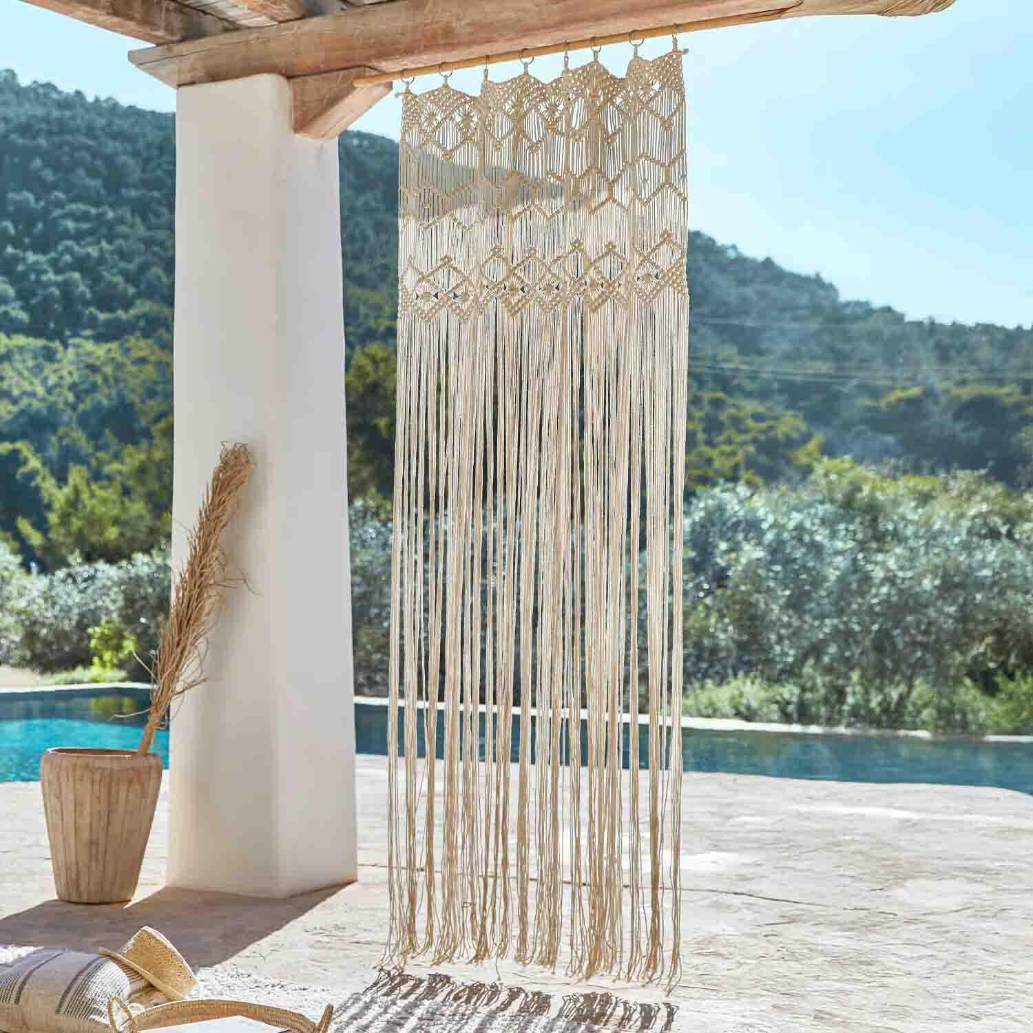 Macramé beige en coton suspendu à une poutre en bois, décoration bohème pour terrasse avec vue piscine