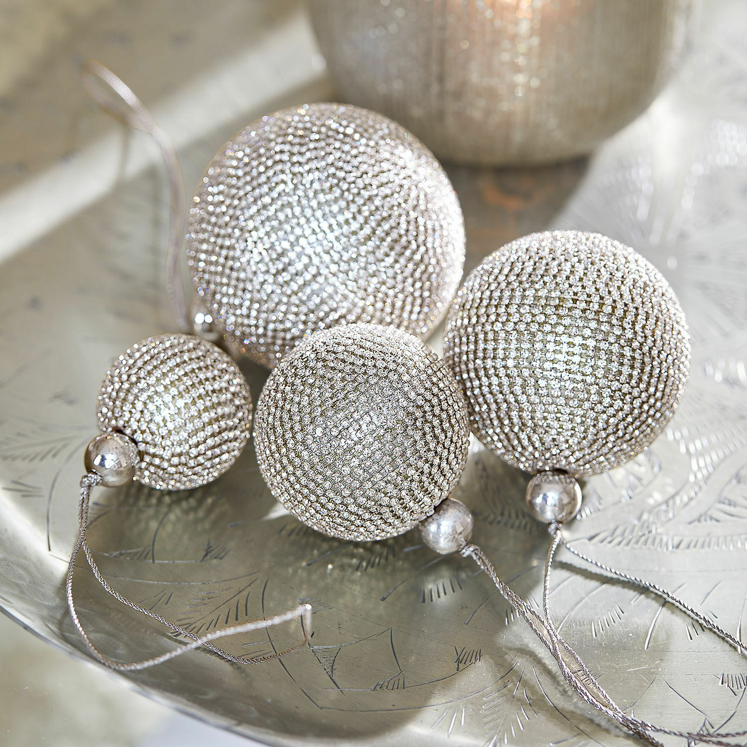 Set de 4 boules de Noël Varnor Ensemble de quatre boules de Noël argentées ornées de petits cristaux sur un plateau métallique décoratif