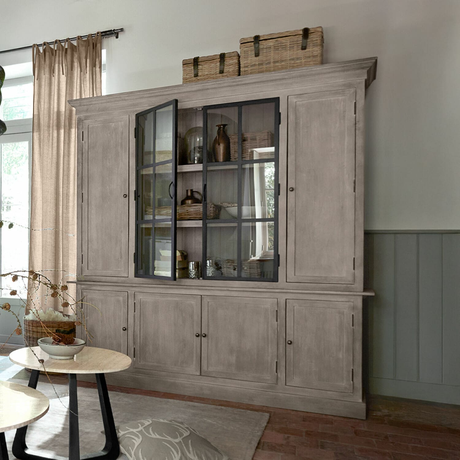 Vaisselier Valandor Grande vitrine en bois gris avec portes vitrées et paniers sur le dessus dans un salon