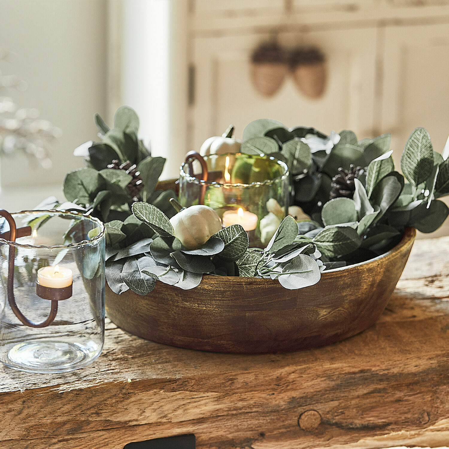 Guirlande Belfays Bol en bois décoratif avec feuillage vert et bougies dans des photophores en verre sur une table