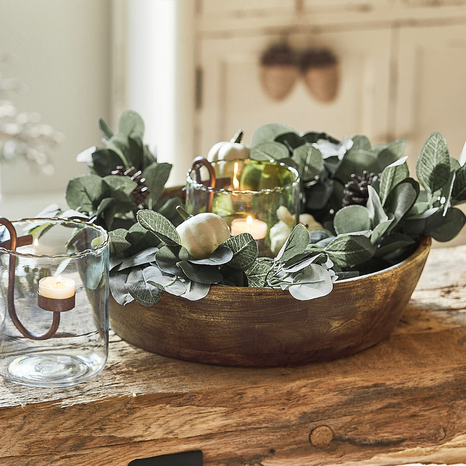 Guirlande Belfays Bol en bois décoratif avec feuillage vert et bougies dans des photophores en verre sur une table