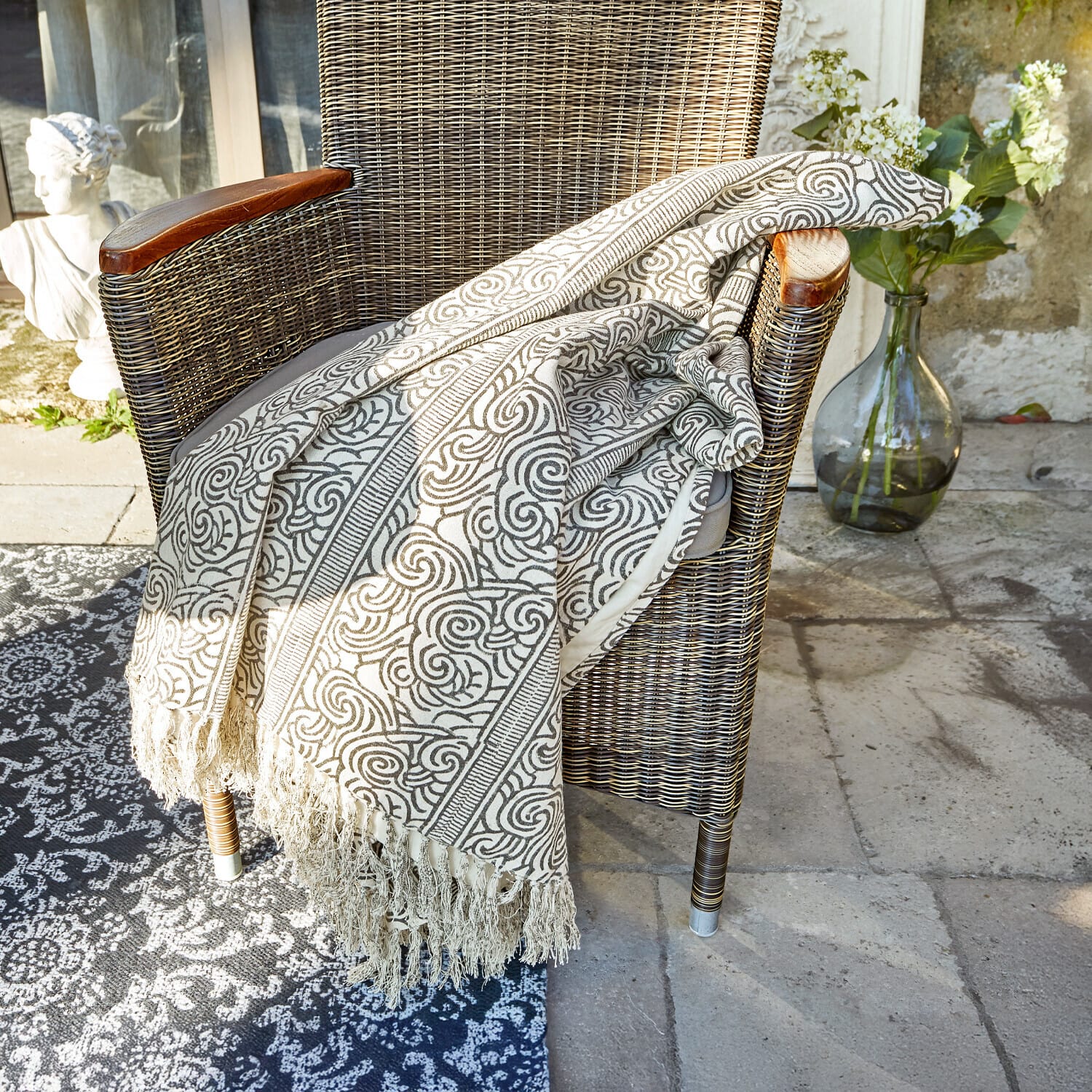 Plaid Ensis Plaid beige à motifs avec franges sur fauteuil en osier, décoration intérieure et extérieure