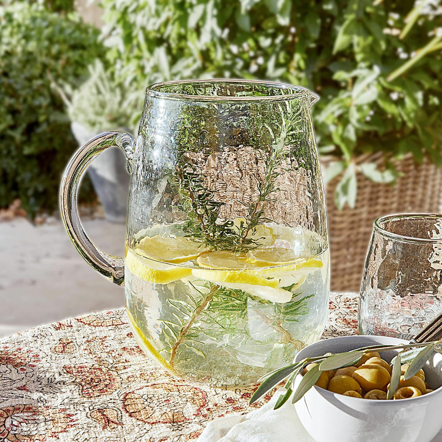 Pichet Rezay Carafe en verre avec eau citronnée et herbes sur nappe décorative, boisson d'été en terrasse