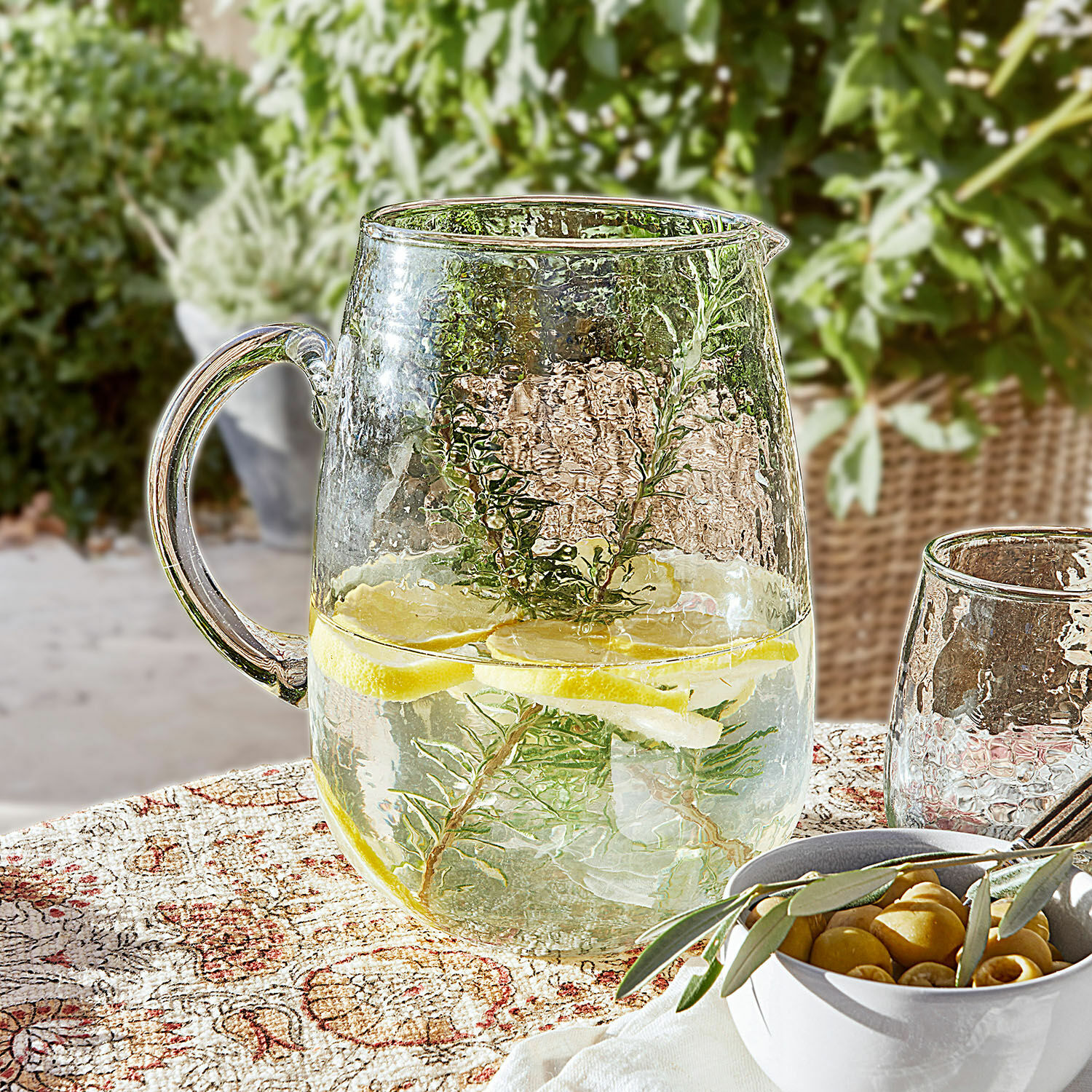Pichet Rezay Carafe en verre avec eau citronnée et herbes sur nappe décorative, boisson d'été en terrasse