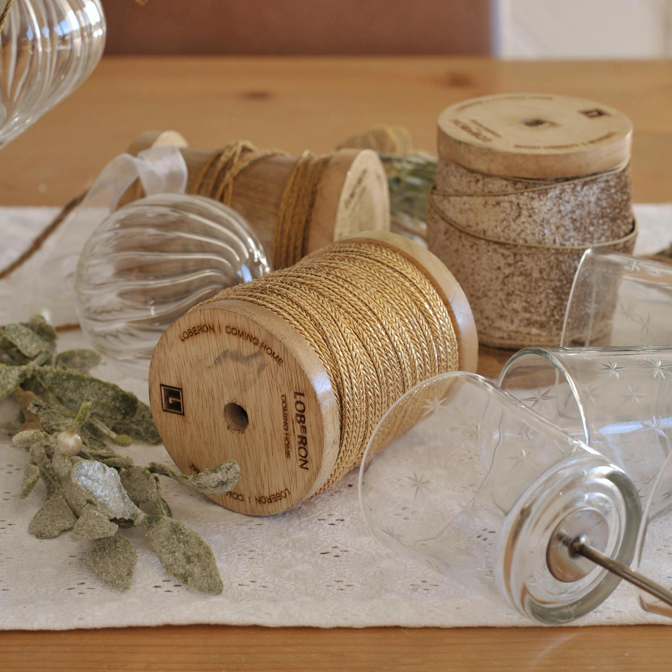 Bobines en bois avec ficelle naturelle et photophores en verre décoratifs sur nappe blanche