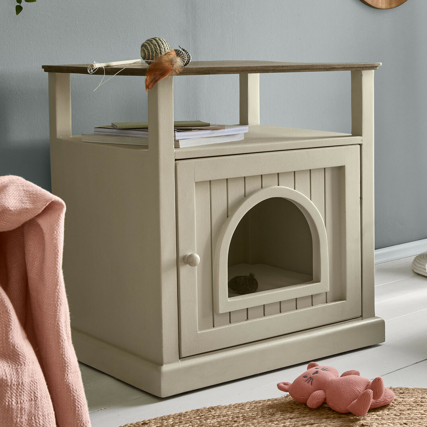 Maison pour chat en bois beige avec étagère pour livres et jouets dans un intérieur moderne